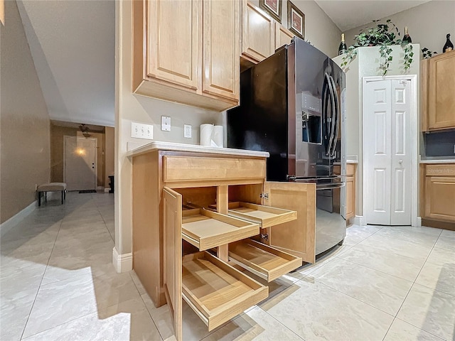 kitchen with light brown cabinets, light tile patterned floors, and black fridge