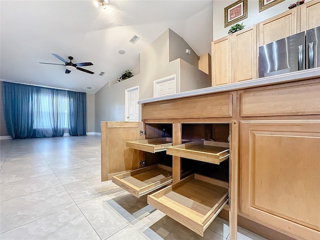 interior space with ceiling fan, high vaulted ceiling, light brown cabinetry, and light tile patterned floors