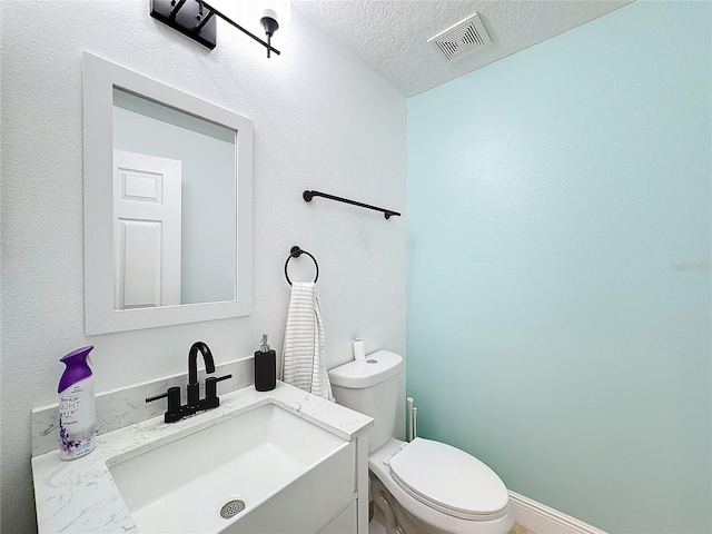 bathroom featuring vanity, toilet, and a textured ceiling