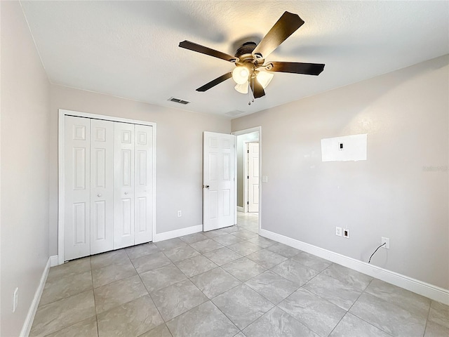 unfurnished bedroom featuring a closet, ceiling fan, a textured ceiling, and light tile patterned flooring