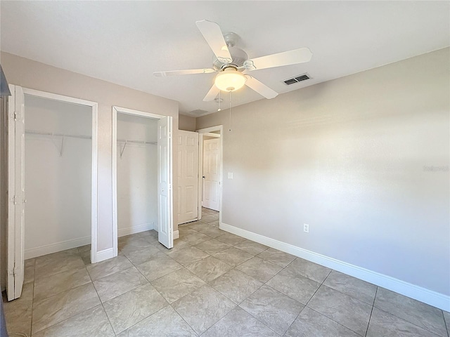 unfurnished bedroom featuring multiple closets and ceiling fan