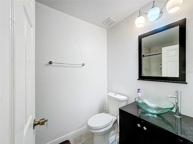 bathroom with a textured ceiling, toilet, walk in shower, vanity, and tile patterned flooring