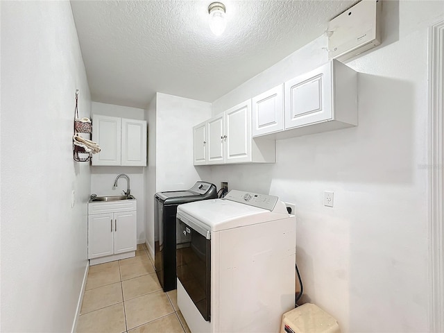 laundry area with independent washer and dryer, sink, light tile patterned flooring, cabinets, and a textured ceiling