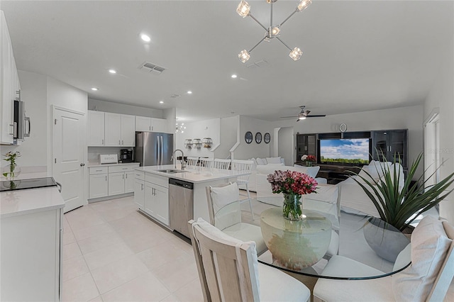 kitchen featuring a center island with sink, white cabinetry, sink, ceiling fan with notable chandelier, and stainless steel appliances