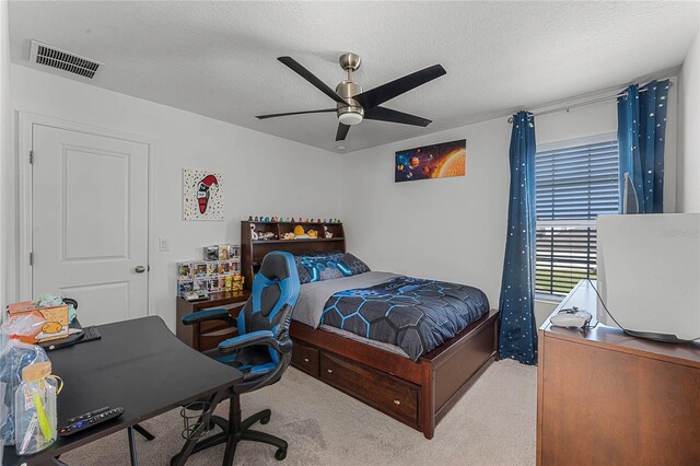 bedroom featuring a textured ceiling, light colored carpet, and ceiling fan