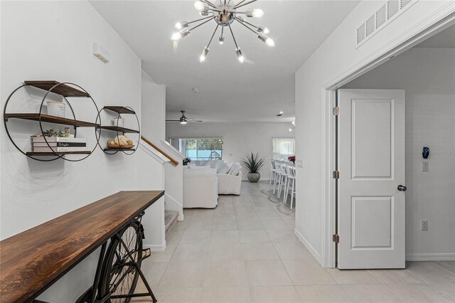 corridor featuring an inviting chandelier and light tile patterned floors