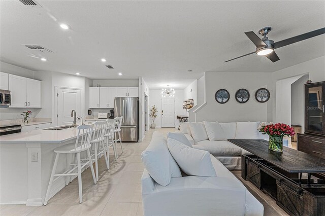 living room with sink, ceiling fan with notable chandelier, and light tile patterned floors