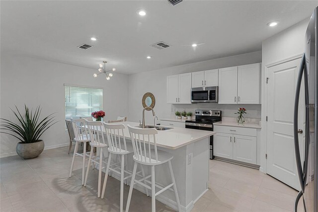 kitchen featuring white cabinets, a kitchen island with sink, stainless steel appliances, and sink