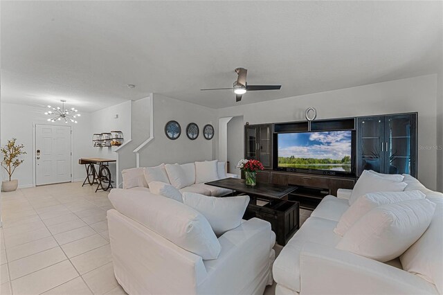 tiled living room featuring ceiling fan with notable chandelier