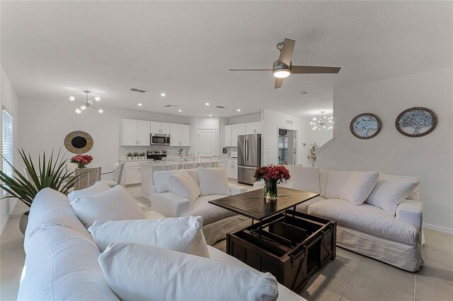 living room with ceiling fan with notable chandelier and light tile patterned floors