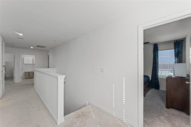 hallway featuring light carpet and a textured ceiling