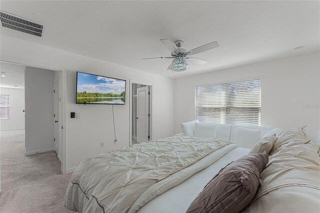 carpeted bedroom featuring a textured ceiling and ceiling fan