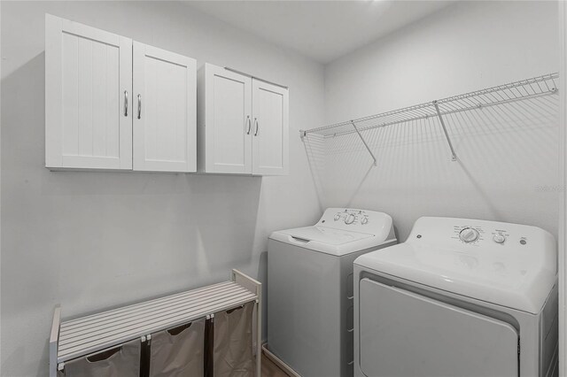 clothes washing area featuring cabinets and washing machine and clothes dryer