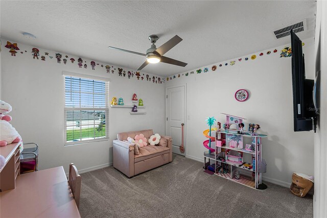 recreation room with ceiling fan, carpet flooring, and a textured ceiling