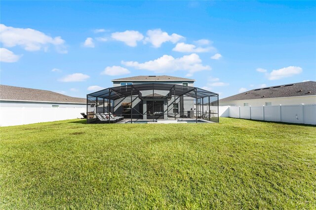 rear view of property featuring a patio area, a swimming pool, a lawn, and a lanai