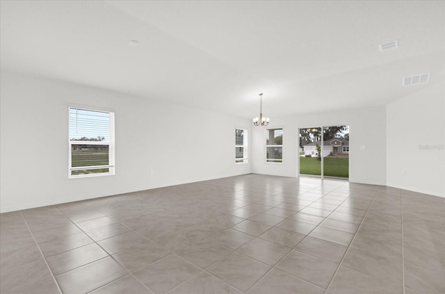 spare room featuring a chandelier, light tile patterned floors, and visible vents