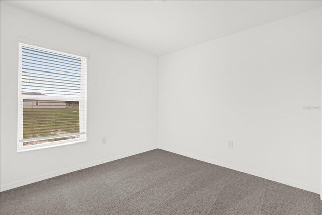 unfurnished room featuring carpet and baseboards