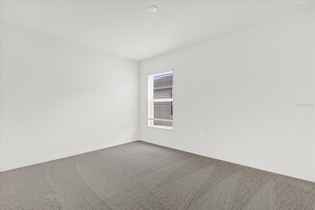 carpeted spare room with baseboards