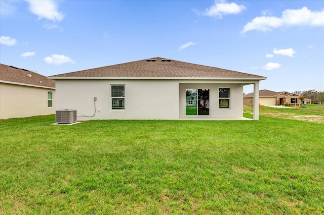 back of property with roof with shingles, a lawn, cooling unit, and stucco siding