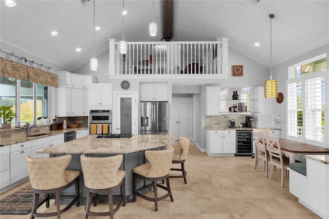 kitchen featuring high vaulted ceiling, stainless steel appliances, a center island, and beverage cooler