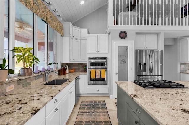 kitchen featuring appliances with stainless steel finishes, white cabinetry, light stone countertops, and sink