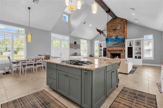 kitchen featuring light stone countertops, gray cabinetry, decorative light fixtures, and high vaulted ceiling