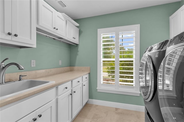 clothes washing area with cabinets, sink, separate washer and dryer, and light tile patterned floors