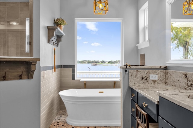 bathroom featuring vanity, a tub, a water view, and a wealth of natural light