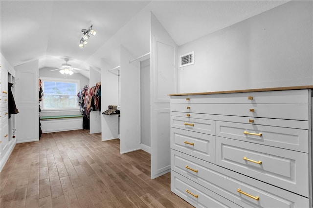 walk in closet with light hardwood / wood-style floors, vaulted ceiling, and ceiling fan