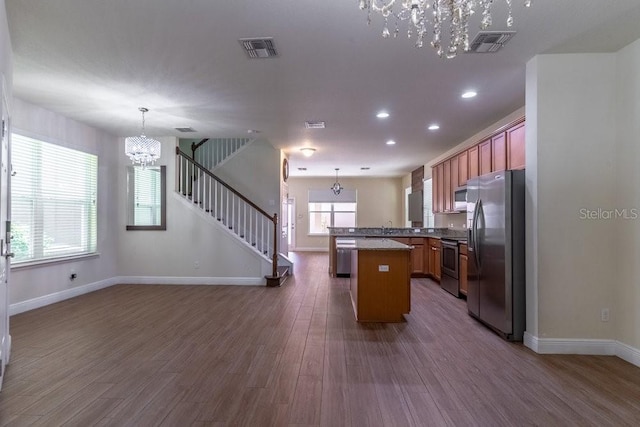 kitchen with decorative light fixtures, stainless steel appliances, a healthy amount of sunlight, and dark hardwood / wood-style flooring