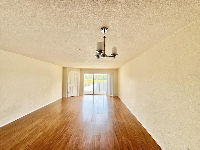 13803 Fairway Island Dr Unit 1627, Orlando, FL 32837 - spare room with a chandelier, a textured wall, wood finished floors, baseboards, and a textured ceiling