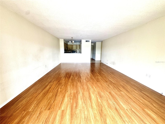 13803 Fairway Island Dr Unit 1627, Orlando, FL 32837 - unfurnished living room featuring light wood-style floors, a chandelier, and a textured ceiling