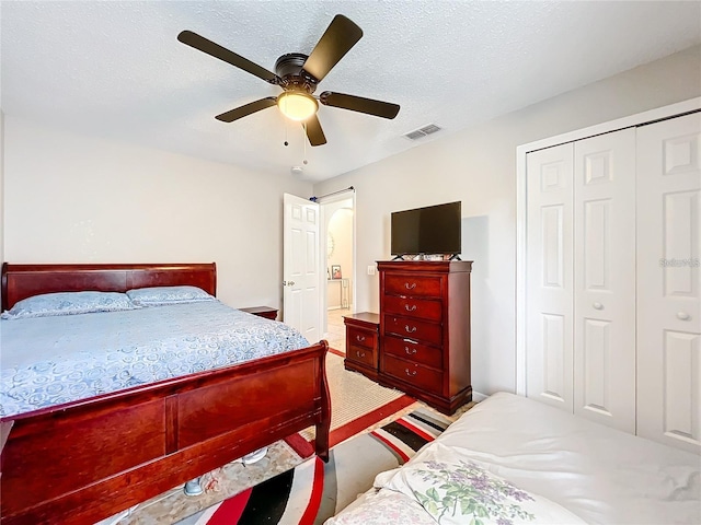 bedroom featuring a closet, a textured ceiling, carpet floors, and ceiling fan