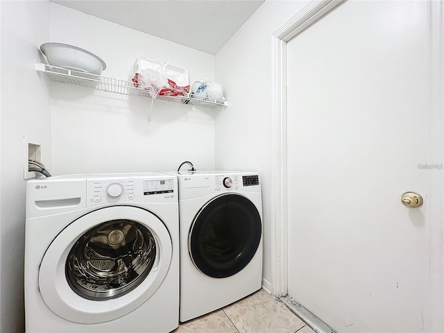 clothes washing area with a textured ceiling, light tile patterned flooring, and washing machine and clothes dryer