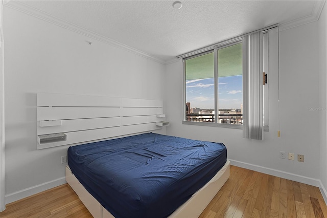 bedroom with crown molding, a textured ceiling, and light wood-type flooring