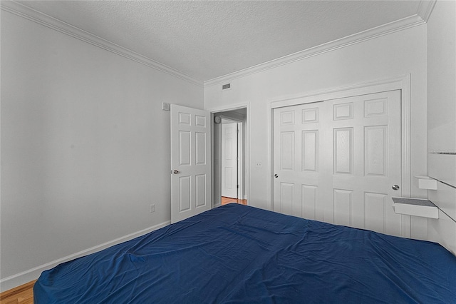 unfurnished bedroom featuring a closet, crown molding, wood-type flooring, and a textured ceiling