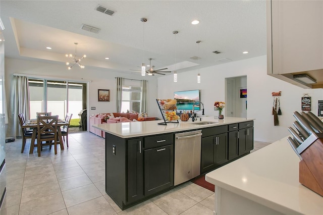 kitchen featuring stainless steel dishwasher, ceiling fan with notable chandelier, sink, decorative light fixtures, and an island with sink