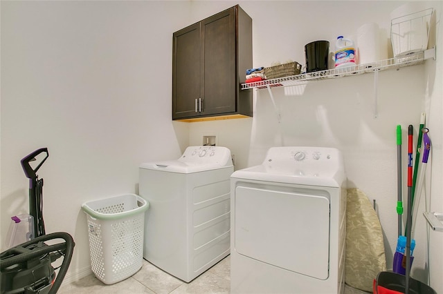 laundry area featuring independent washer and dryer, cabinets, and light tile patterned flooring