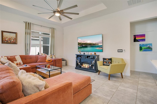 living room featuring light tile patterned floors, a tray ceiling, and ceiling fan