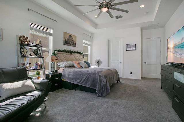 carpeted bedroom with ceiling fan and a tray ceiling