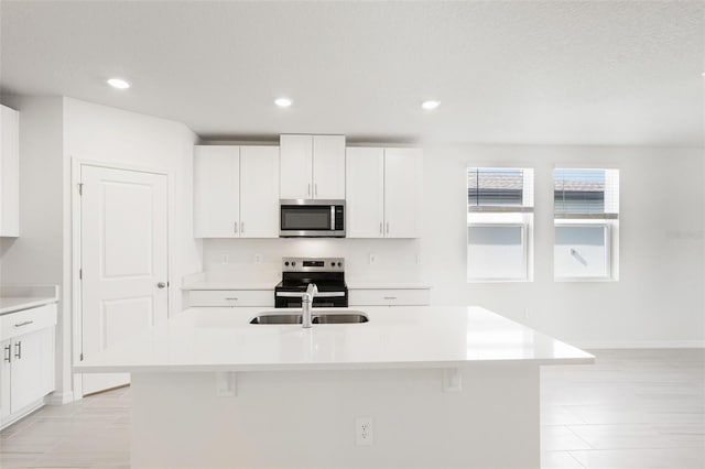 kitchen featuring a center island with sink, white cabinets, stainless steel appliances, and sink