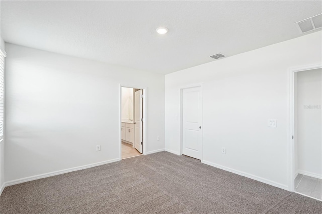 unfurnished bedroom with ensuite bathroom and light colored carpet