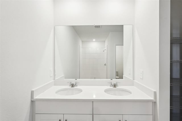 bathroom with a tile shower, vanity, and toilet