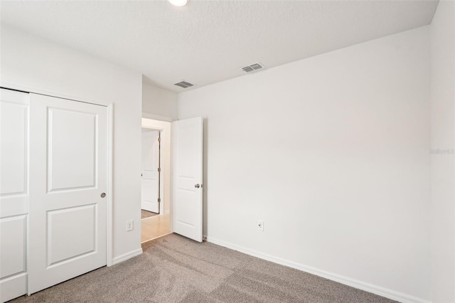 unfurnished bedroom featuring light carpet and a closet