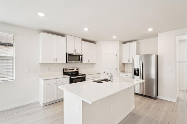 kitchen with white cabinets, sink, stainless steel appliances, and a center island with sink