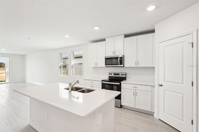 kitchen featuring white cabinets, appliances with stainless steel finishes, a kitchen island with sink, and sink