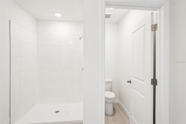 bathroom featuring a tile shower and toilet