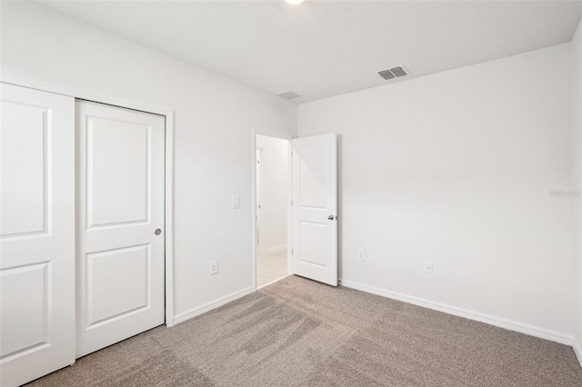 unfurnished bedroom featuring light carpet and a closet