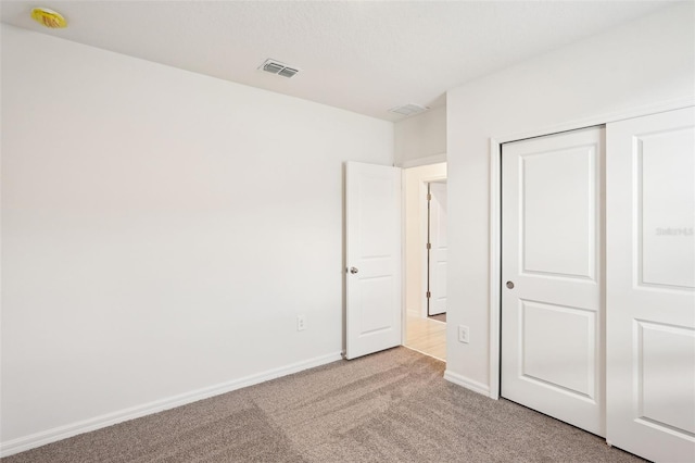 unfurnished bedroom featuring light carpet and a closet