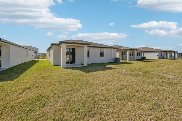 back of property with central AC unit and a lawn